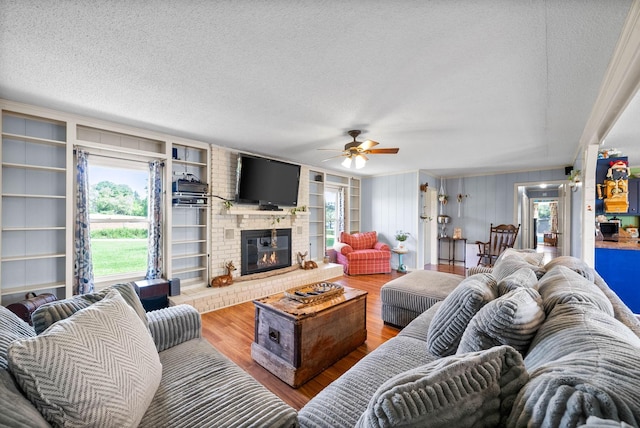 living area with a fireplace, a textured ceiling, and wood finished floors