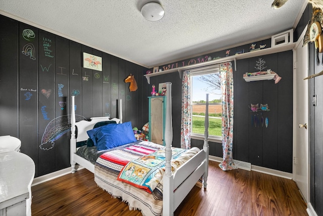 bedroom with baseboards, a textured ceiling, crown molding, and wood finished floors