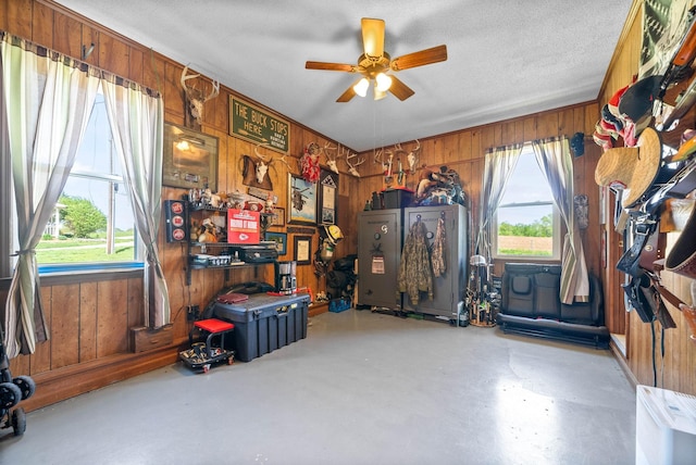 interior space featuring wood walls, ceiling fan, and concrete flooring