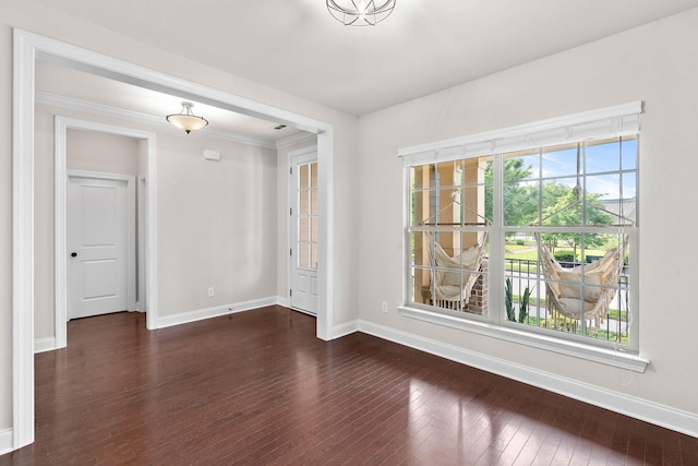 unfurnished room featuring baseboards, dark wood finished floors, and ornamental molding