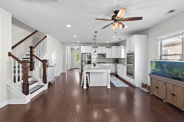 kitchen featuring a ceiling fan, appliances with stainless steel finishes, a healthy amount of sunlight, and a breakfast bar