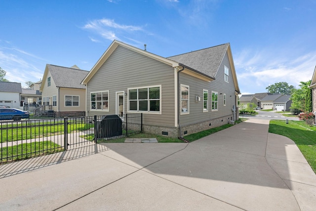 back of property with fence, a residential view, roof with shingles, crawl space, and a lawn