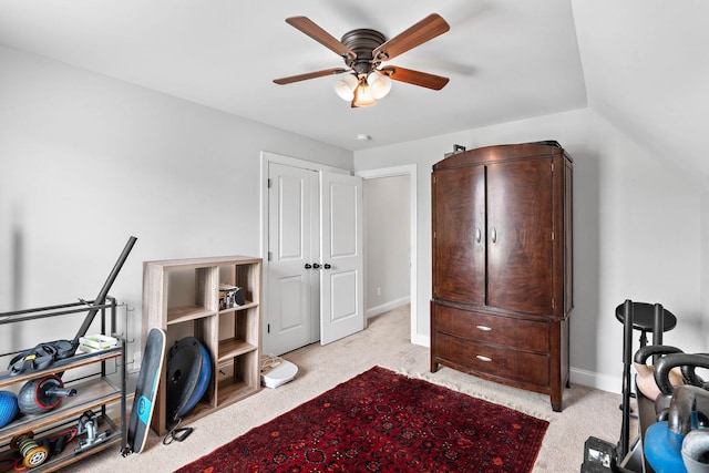 interior space featuring baseboards, a ceiling fan, and light colored carpet