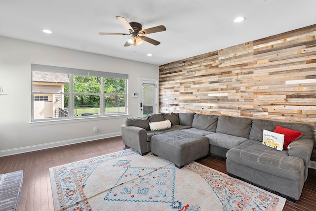 living area featuring wooden walls, ceiling fan, recessed lighting, baseboards, and hardwood / wood-style flooring