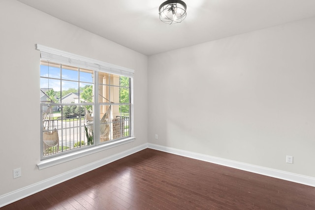 unfurnished room with baseboards and dark wood-style floors