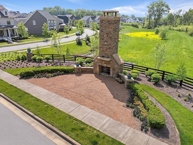 exterior space with an outdoor stone fireplace, fence, and a residential view
