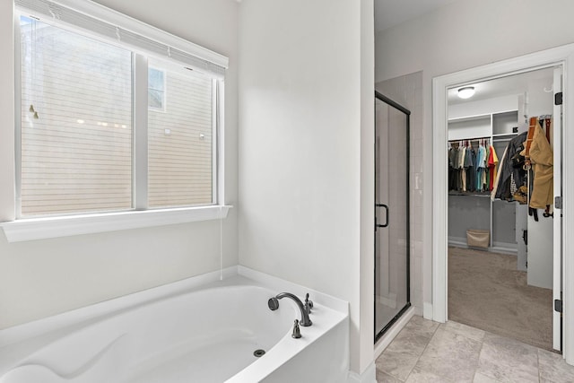 bathroom featuring a garden tub, a walk in closet, and a stall shower