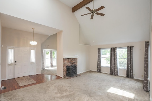 unfurnished living room featuring high vaulted ceiling, carpet flooring, a ceiling fan, beam ceiling, and a brick fireplace