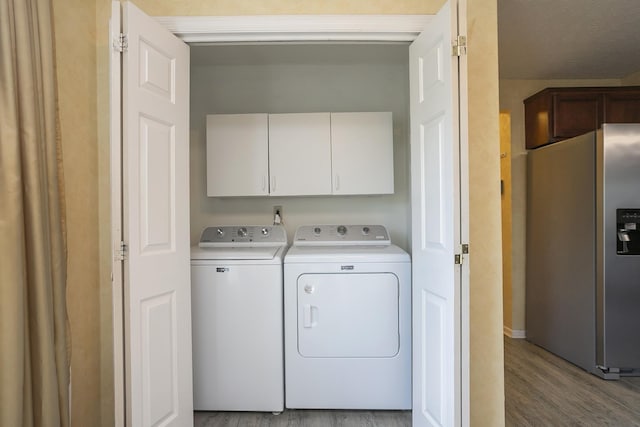 laundry area featuring separate washer and dryer, wood finished floors, and cabinet space