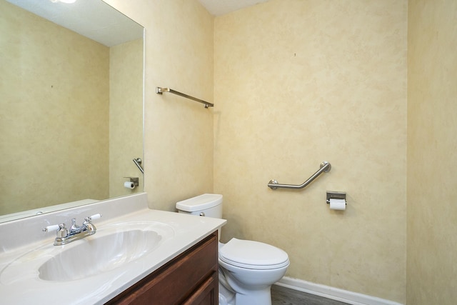 bathroom with toilet, vanity, and wood finished floors
