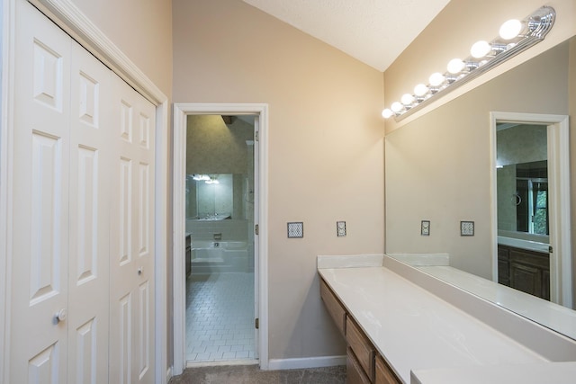 bathroom featuring vaulted ceiling, vanity, baseboards, and tile patterned flooring