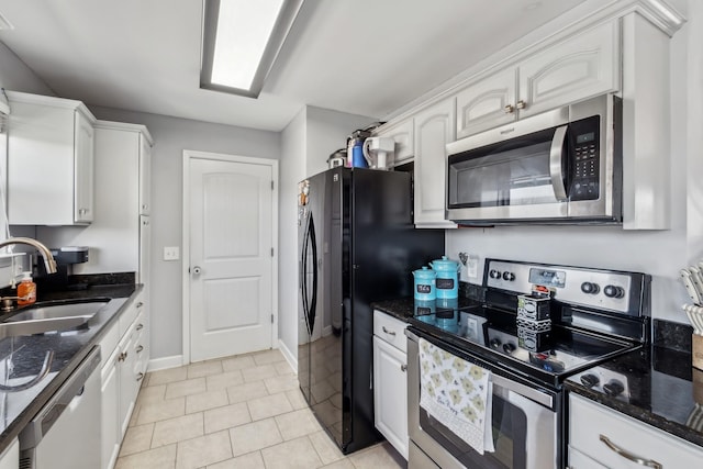 kitchen with a sink, appliances with stainless steel finishes, dark stone counters, and white cabinetry
