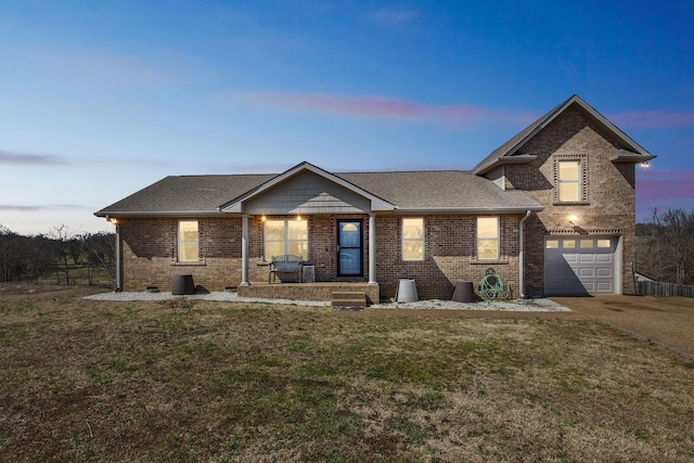 view of front of home featuring a garage, a lawn, driveway, and brick siding