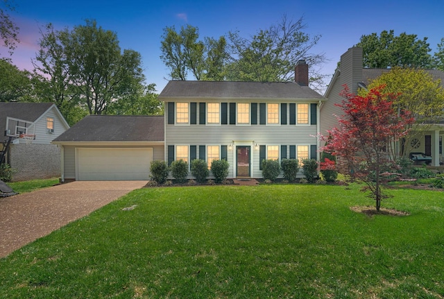 colonial inspired home with a yard, an attached garage, concrete driveway, and a chimney