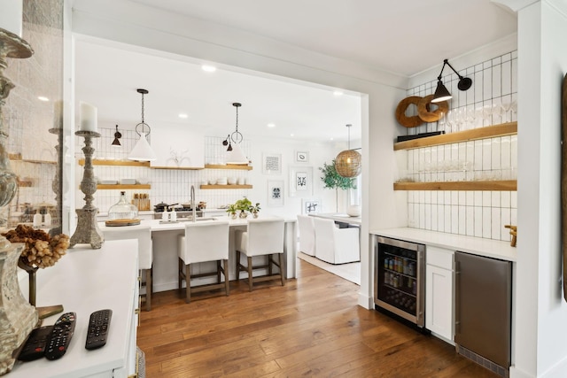 bar with a sink, wine cooler, backsplash, refrigerator, and hardwood / wood-style flooring