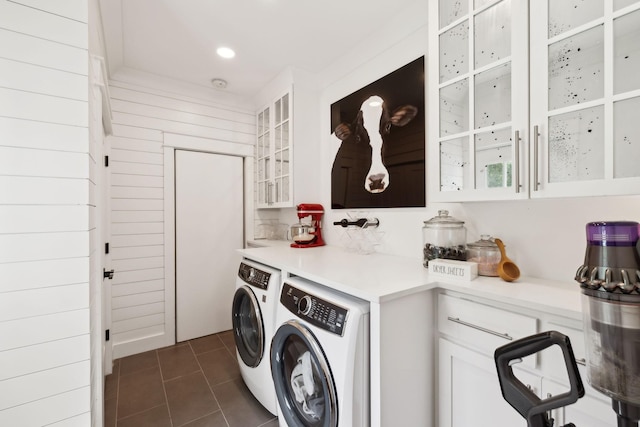 clothes washing area with dark tile patterned floors, washer and clothes dryer, and cabinet space