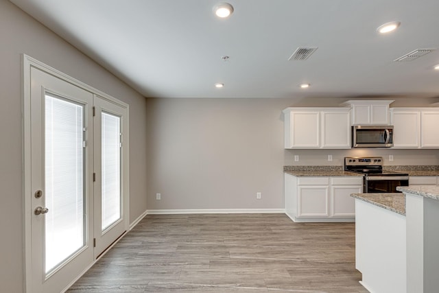 kitchen with white cabinets, stainless steel appliances, visible vents, and plenty of natural light