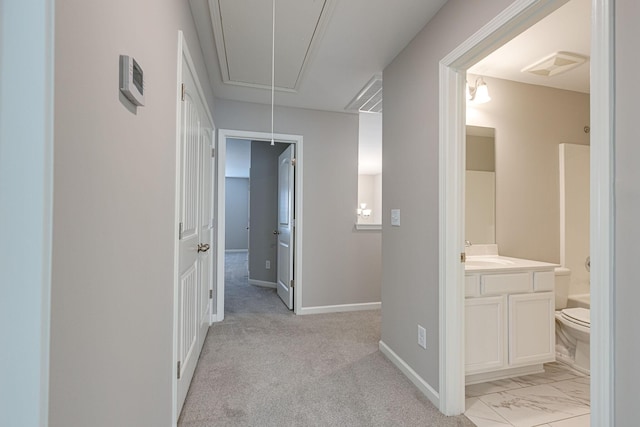 hall featuring baseboards, attic access, and a sink