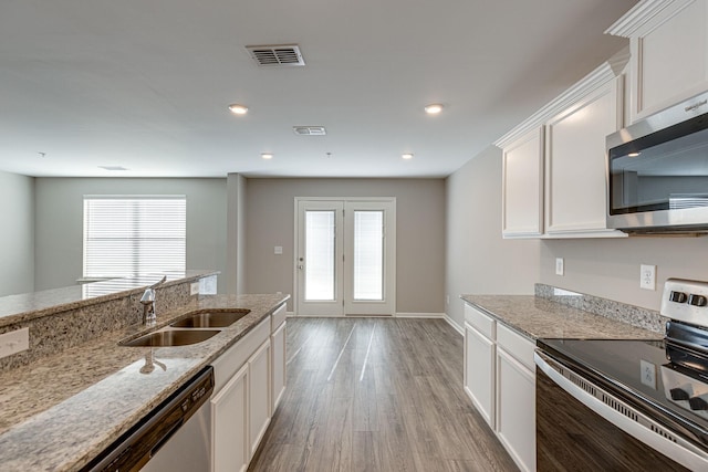 kitchen featuring white cabinets, appliances with stainless steel finishes, a sink, light wood finished floors, and visible vents