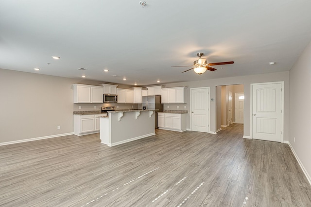 kitchen with baseboards, a breakfast bar area, stainless steel appliances, and open floor plan