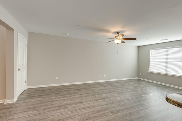 spare room featuring visible vents, baseboards, ceiling fan, and wood finished floors
