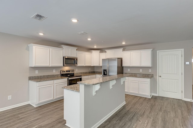 kitchen with light wood-style floors, appliances with stainless steel finishes, white cabinetry, and visible vents