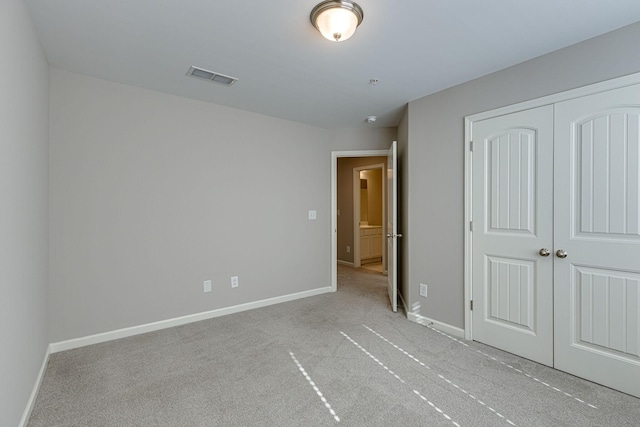 unfurnished bedroom featuring a closet, baseboards, light colored carpet, and visible vents