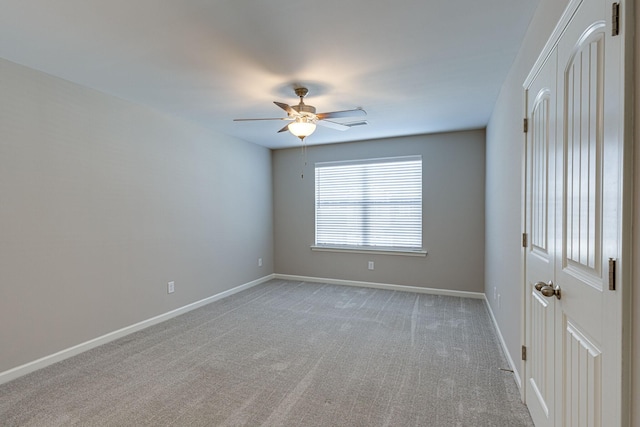 unfurnished room featuring baseboards, ceiling fan, and light colored carpet