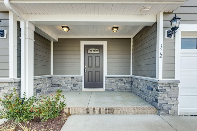 view of exterior entry featuring covered porch and stone siding