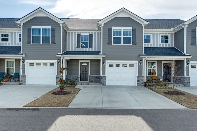 view of front facade with a garage, concrete driveway, a porch, and stone siding