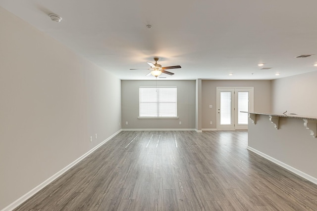 unfurnished living room featuring a ceiling fan, baseboards, and wood finished floors