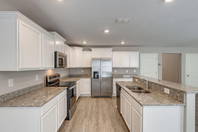 kitchen featuring white cabinets, stainless steel appliances, a sink, and light wood finished floors