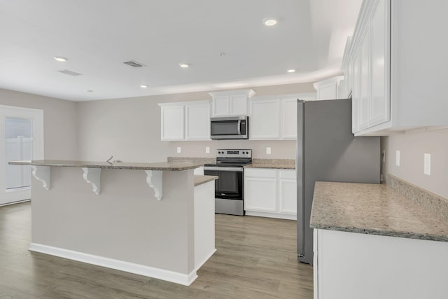 312 Mattie Ln, Spring Hill, TN 37174 - kitchen with stainless steel appliances, a breakfast bar area, light wood-style flooring, white cabinets, and recessed lighting