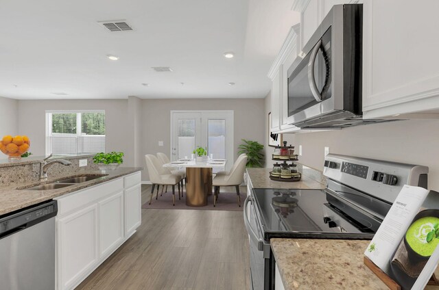 312 Mattie Ln, Spring Hill, TN 37174 - kitchen with stainless steel appliances, a sink, white cabinets, light wood-type flooring, and light stone counters