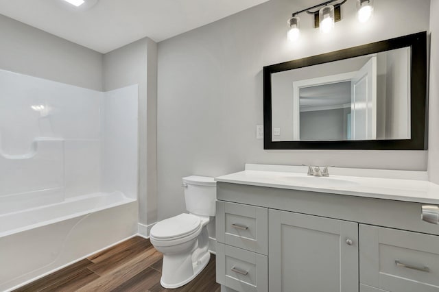 bathroom featuring shower / bath combination, wood finished floors, baseboards, vanity, and toilet
