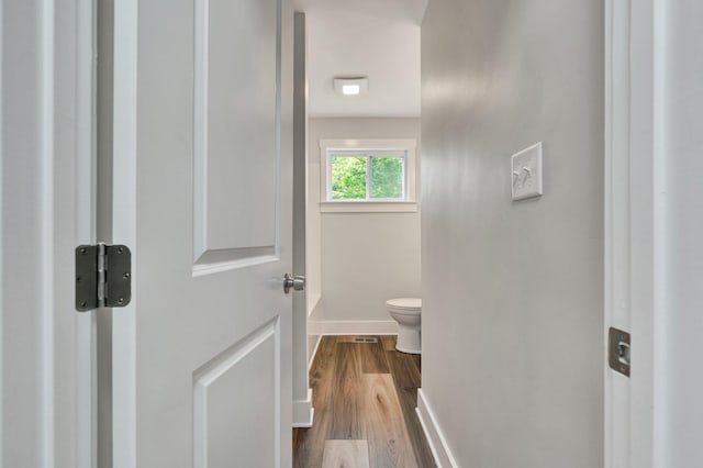 bathroom featuring baseboards, wood finished floors, and toilet