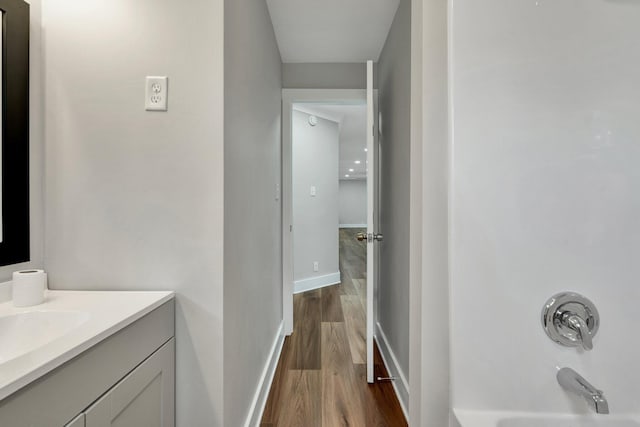 full bath featuring vanity, baseboards, wood finished floors, and  shower combination