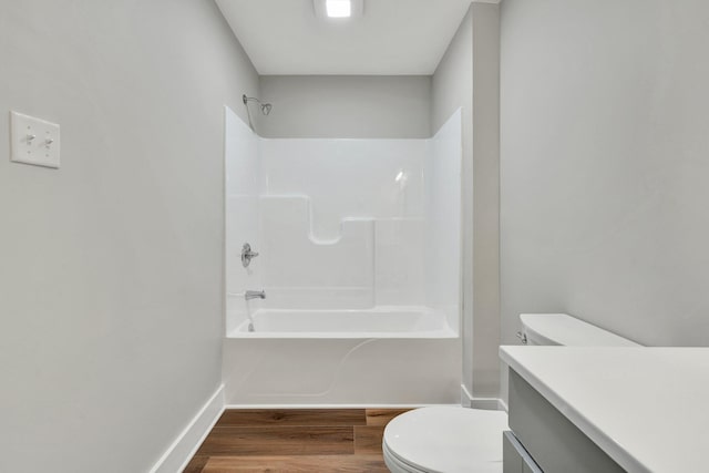 full bath with shower / tub combination, wood finished floors, vanity, baseboards, and toilet