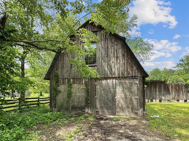 view of barn with fence and a yard