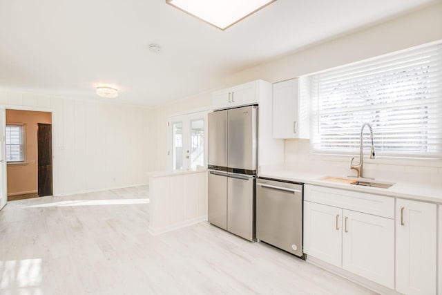 kitchen featuring a sink, light countertops, stainless steel appliances, and white cabinetry
