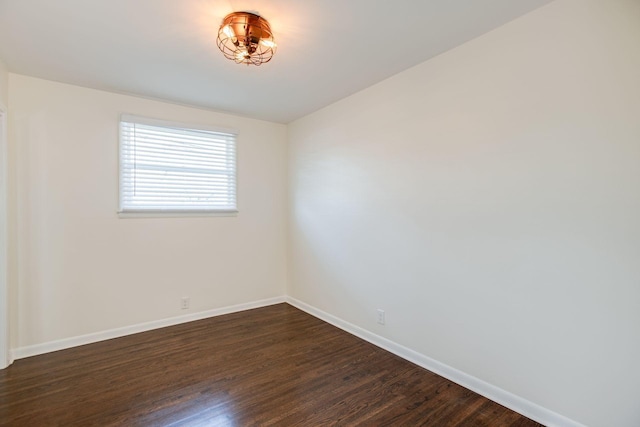 empty room with baseboards and dark wood-type flooring