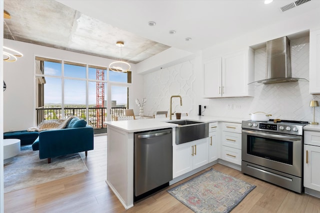 1510 Demonbreun St Unit 807, Nashville, TN 37203 - kitchen with wall chimney range hood, visible vents, appliances with stainless steel finishes, tasteful backsplash, and light wood-style flooring