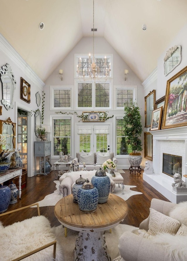 living room with high vaulted ceiling, a fireplace, wood finished floors, and a notable chandelier