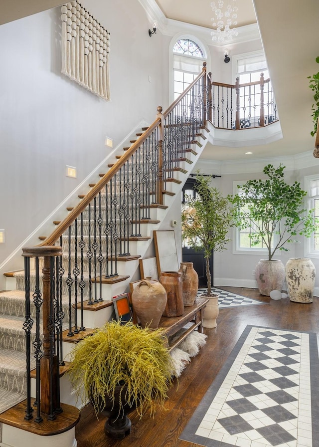 stairs featuring crown molding, wood finished floors, and a wealth of natural light
