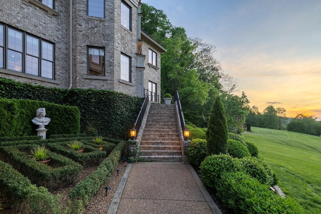 view of exterior entry featuring a lawn and brick siding