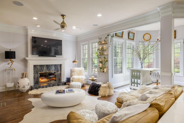 living room with a ceiling fan, crown molding, a fireplace, wood finished floors, and baseboards