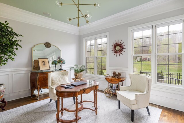 living area featuring crown molding, a wainscoted wall, a notable chandelier, and wood finished floors