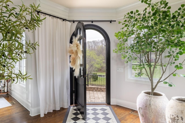 entryway with baseboards, ornamental molding, and wood finished floors