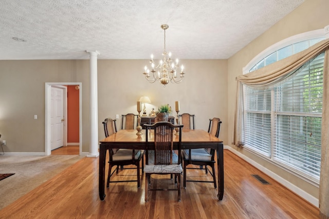 dining room with baseboards, light wood finished floors, a textured ceiling, and a chandelier