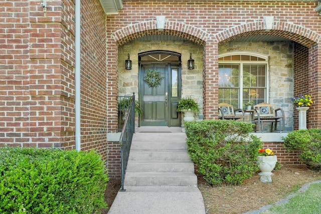 view of exterior entry with stone siding and brick siding